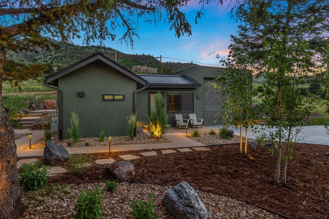 The Guesthouse at dusk with softly lit landscaping and mountains behind
