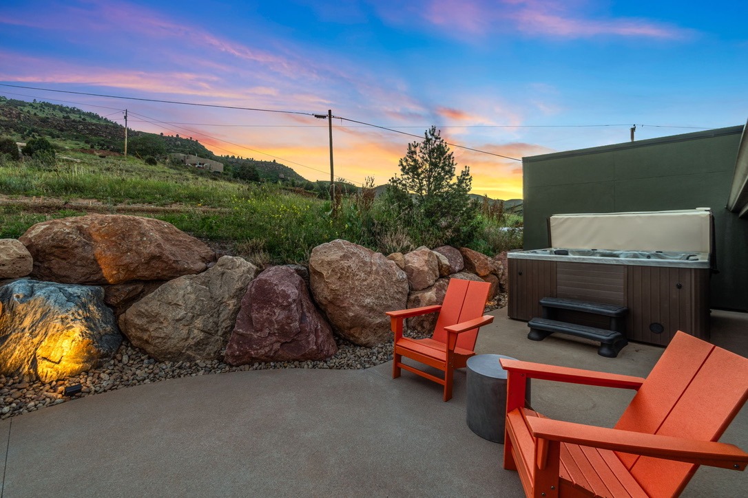 Guesthouse patio at sunset with the hot tub, red boulders and orange Adirondack chairs
