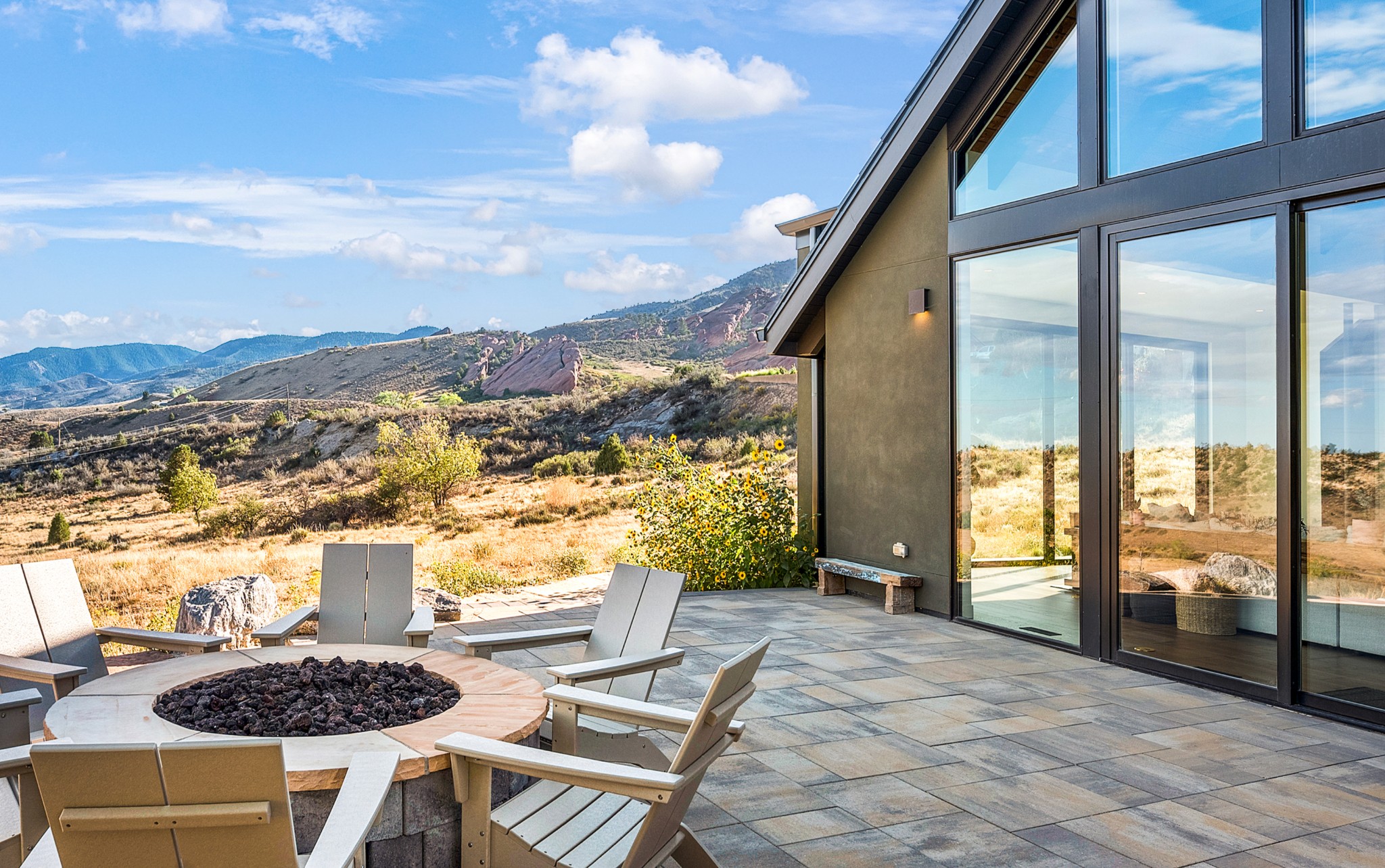 Fire pit and chairs on the patio, the glass-fronted house at right and the Red Rocks landscape beyond